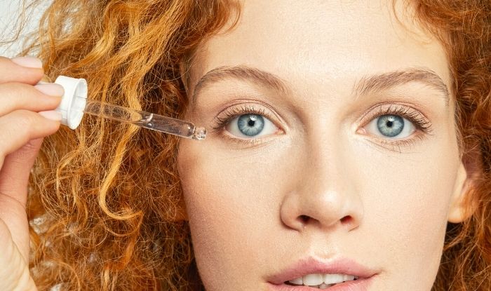 Mujer poniéndose gotas en el rostro para tratamiento facial.